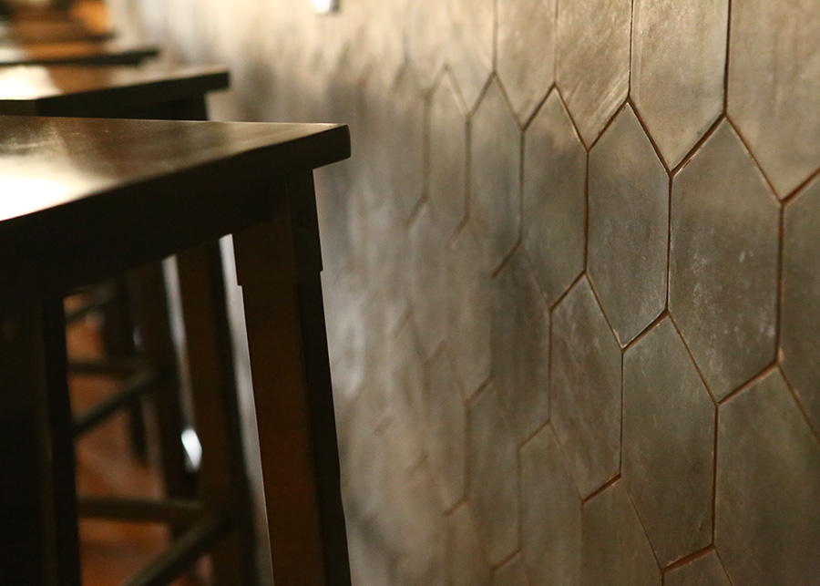 A closeup of the slate honeycomb tiles that line the bar